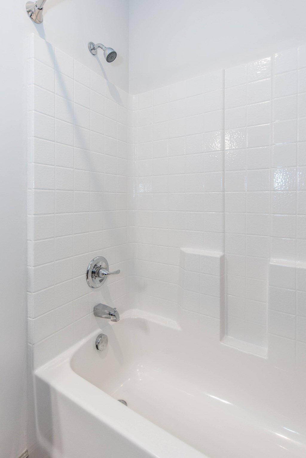 a bathroom with white tile and a white bathtub at The Whitworth, Virginia, 23185