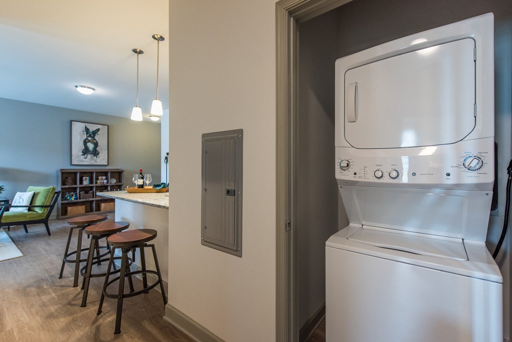 a kitchen with a washer and dryer and a bar with stools at The Whitworth, Williamsburg, VA