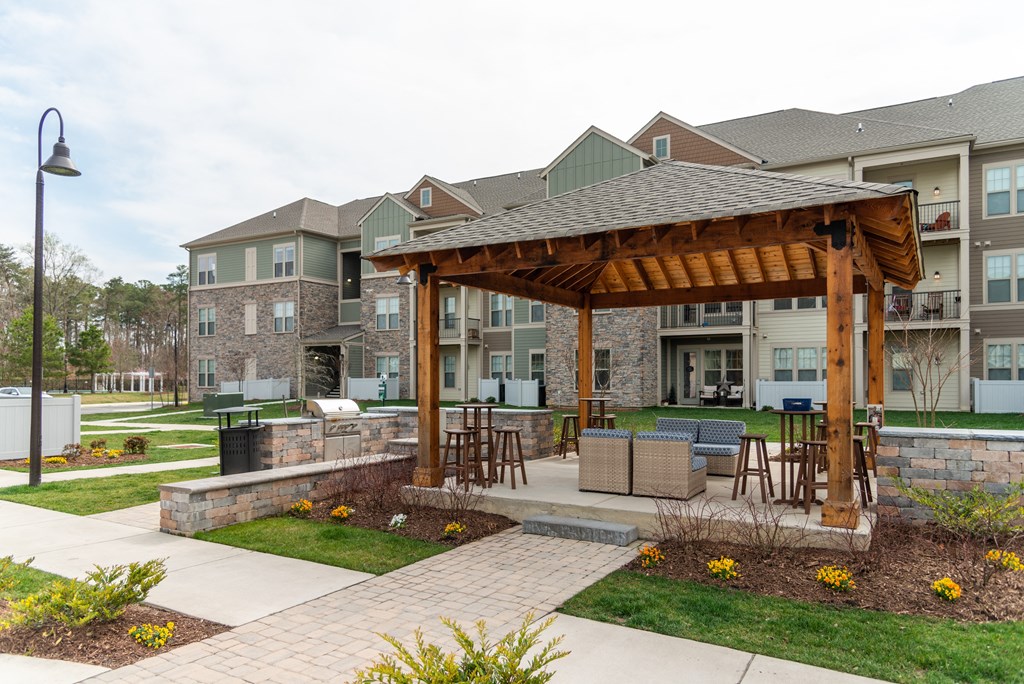 a large wooden pavilion with a stone wall in front of an apartment complex at The Whitworth, Williamsburg, VA