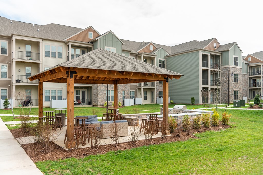 a large wooden pavilion with a seating area in front of an apartment complex at The Whitworth, Virginia, 23185