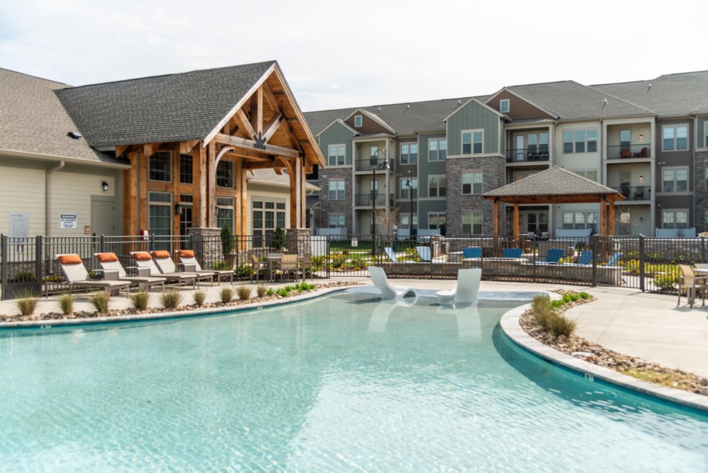 a swimming pool with lounge chairs and a lazy river in front of an apartment building at The Whitworth, Virginia
