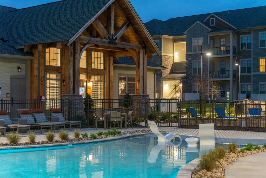 a swimming pool with lounge chairs and a chair in front of an apartment building at The Whitworth, Williamsburg, VA, 23185