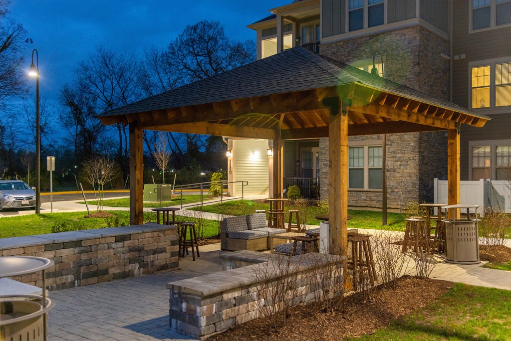 a pavilion with a seating area and a fire pit in front of a building at The Whitworth, Williamsburg, 23185