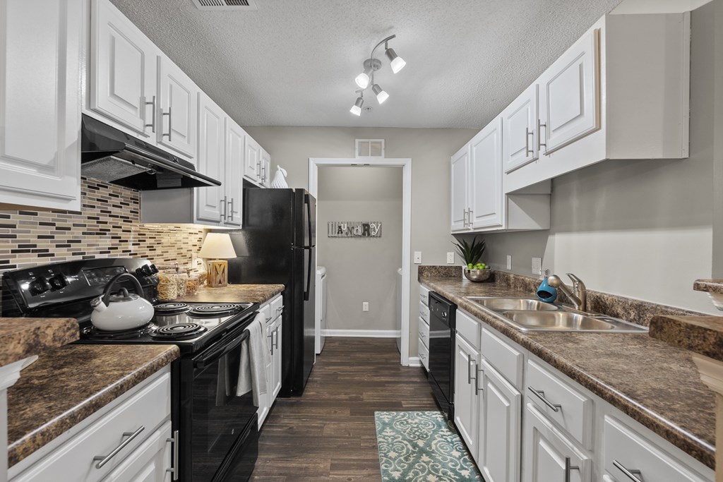 A kitchen with black appliances and white cabinets