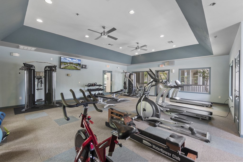 A gym with a variety of equipment including treadmills, stationary bikes, and weight machines