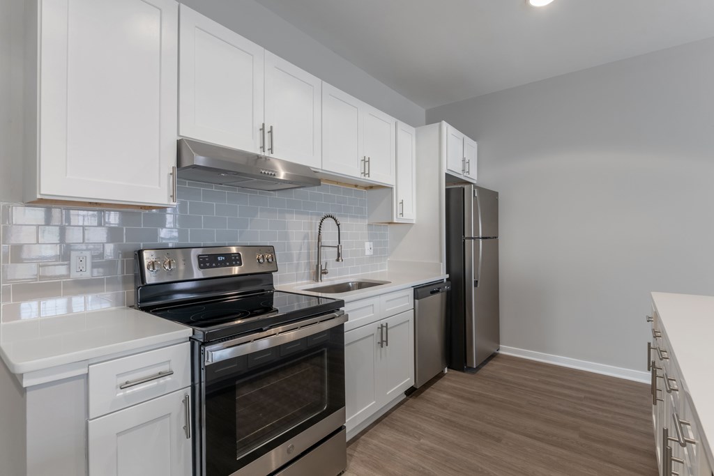 an empty kitchen with white cabinets and stainless steel appliances