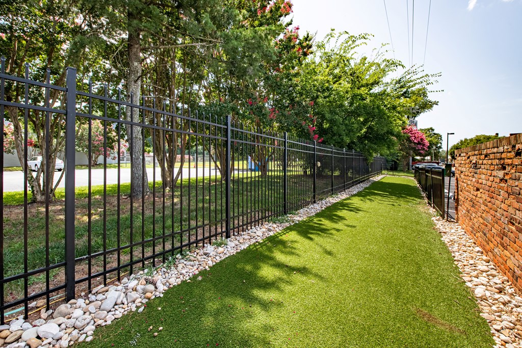 a black wrought iron fence in front of a green lawn and trees at Mayton Transfer Lofts in Petersburg, Virginia