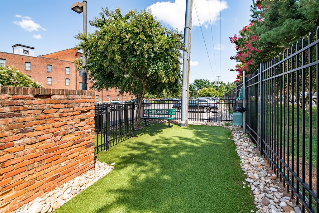 a yard with a bench in front of a black fence at Mayton Transfer Lofts in Virginia 23803