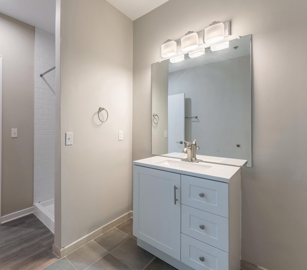 A white bathroom vanity with a mirror and lights above it.