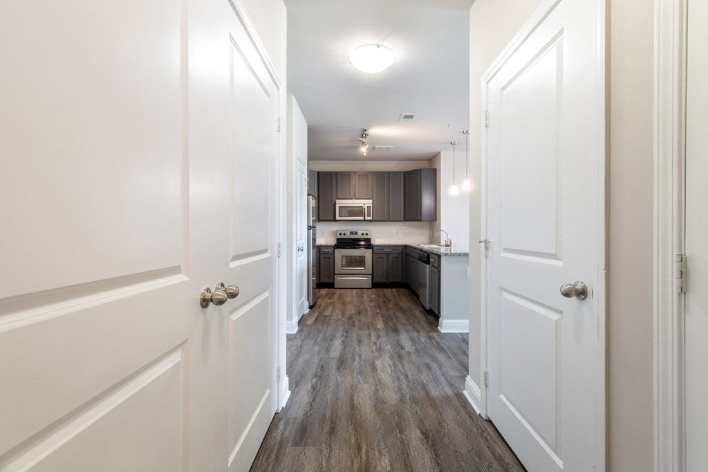 A long hallway with white doors on either side leading to a kitchen at Streets of Greenbrier, Chesapeake, VA, 23320