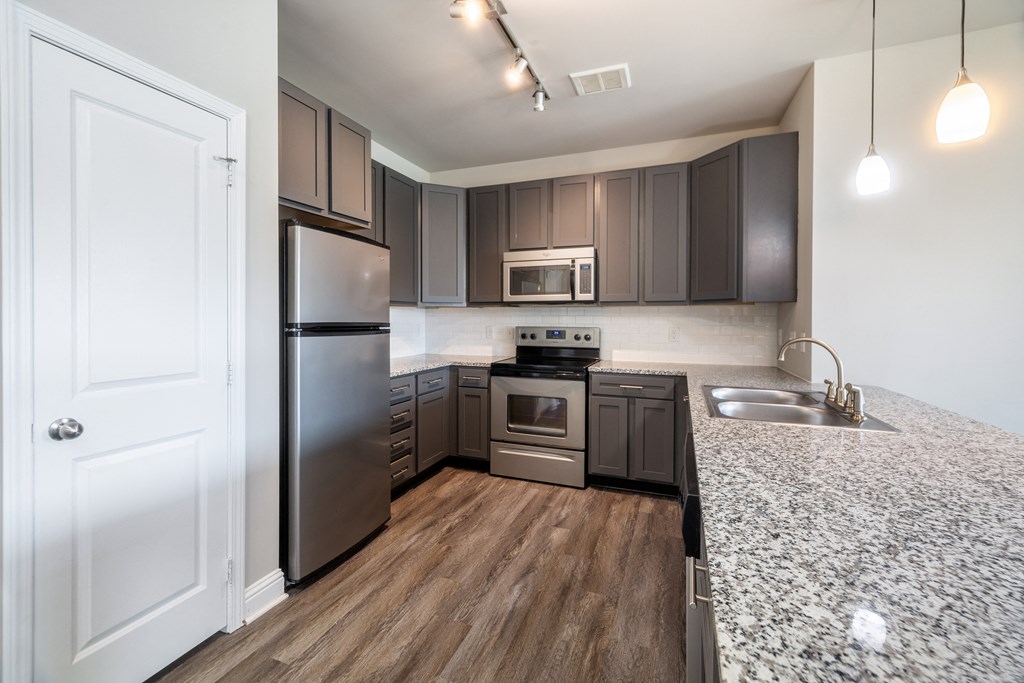 A modern kitchen with dark brown cabinets and stainless steel appliances at Streets of Greenbrier, Chesapeake, 23320