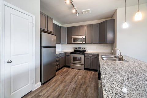 A modern kitchen with dark brown cabinets and stainless steel appliances.