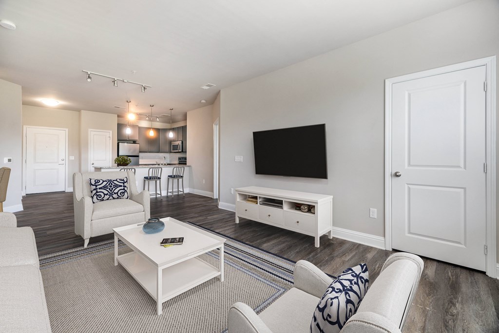 A living room with a white couch, a coffee table, and a television at Streets of Greenbrier, Chesapeake, VA, 23320