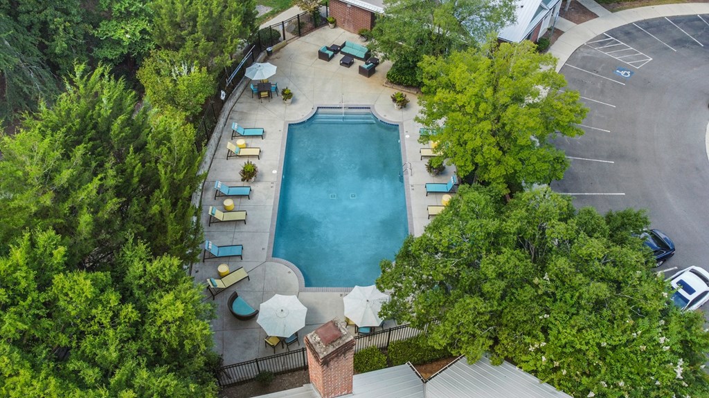 An aerial view of a pool surrounded by trees and chairs