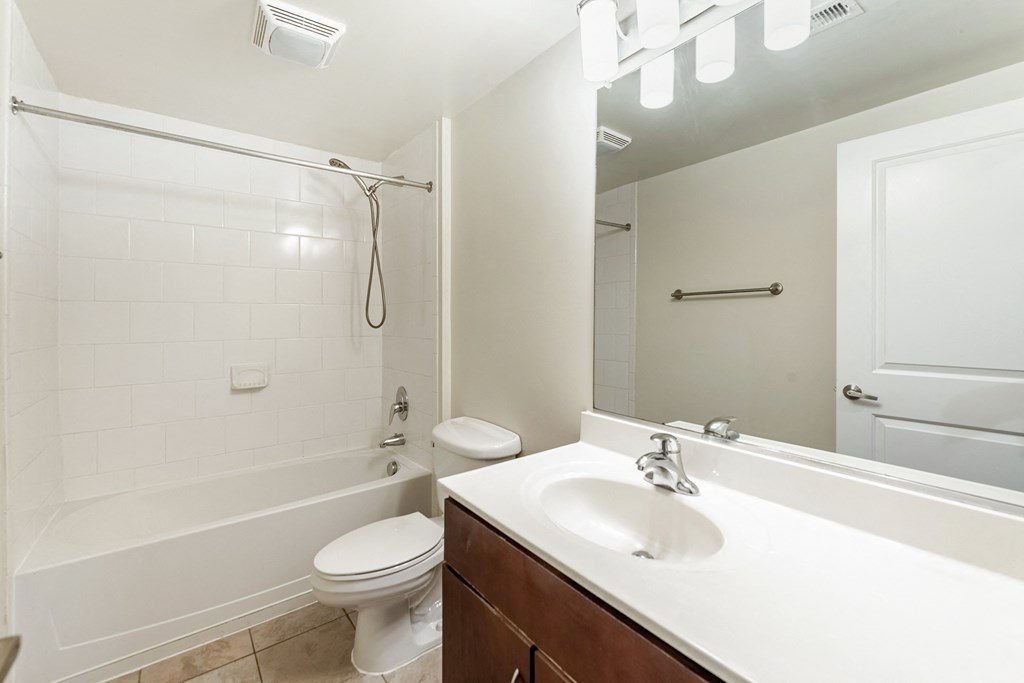 a bathroom with a sink toilet and shower and a mirror at Mayton Transfer Lofts in VA 23803