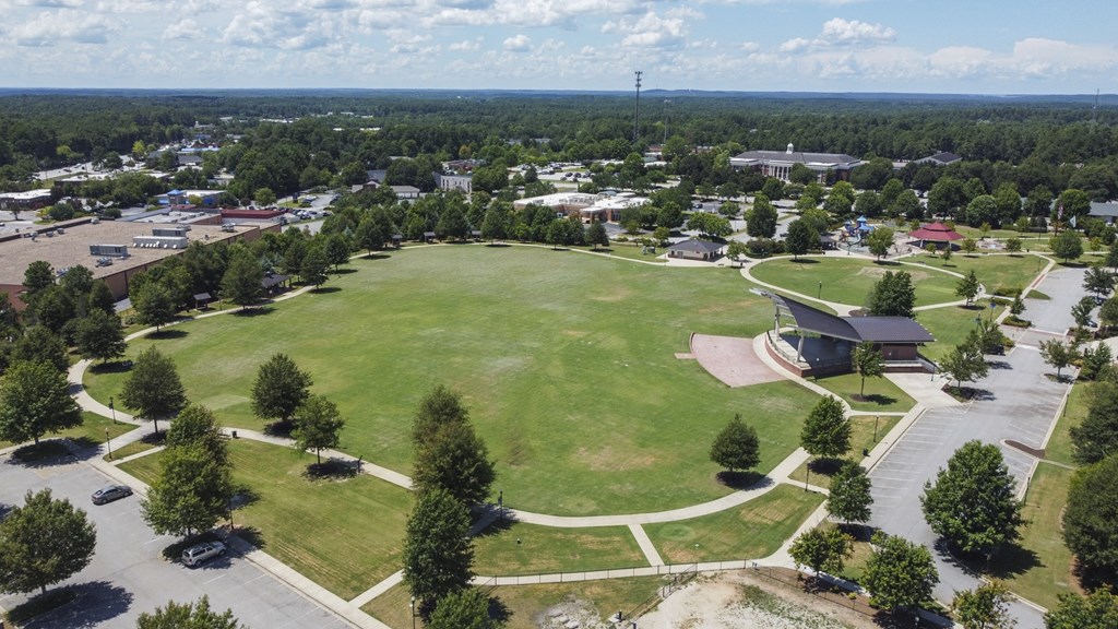 A large grassy field with a building and trees in the distance
