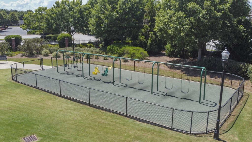 A playground with a green fence and a trampoline