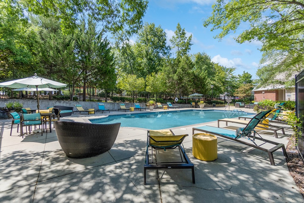 A sunny day at the pool with a green umbrella and blue chairs