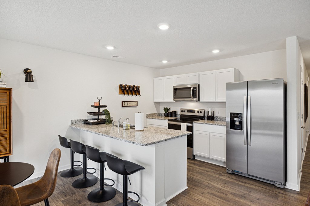 a kitchen with stainless steel appliances and a counter top with bar stools a kitchen with stainless steel appliances and a counter top with bar stools at Summit Place Apartments, Oak Ridge, TN, 37830