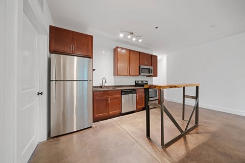A kitchen with a stainless steel refrigerator and wooden cabinets.