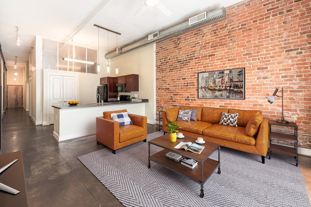 a living room with a brick wall and a couch at Mayton Transfer Lofts in VA 23803