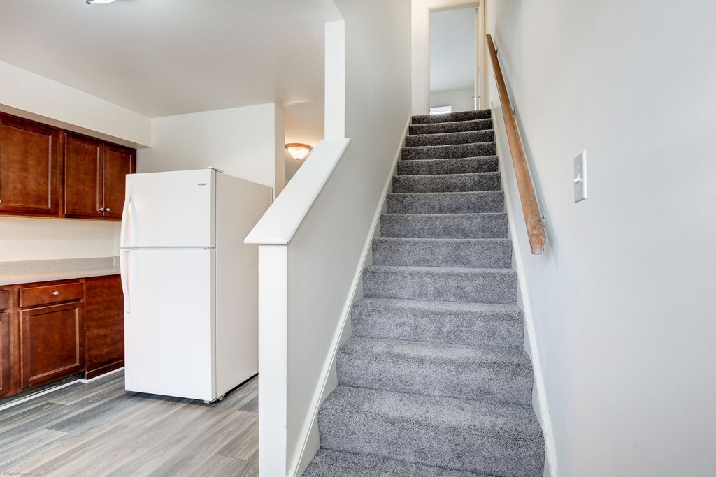 A staircase with a grey carpeted runner and white walls.