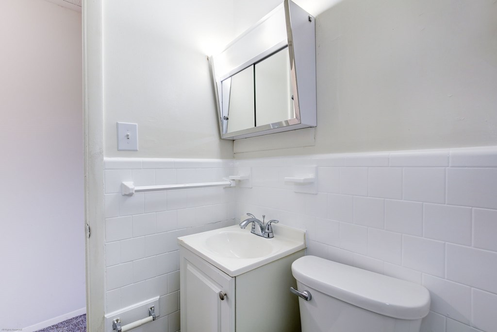 A white bathroom with a toilet, sink, and medicine cabinet.