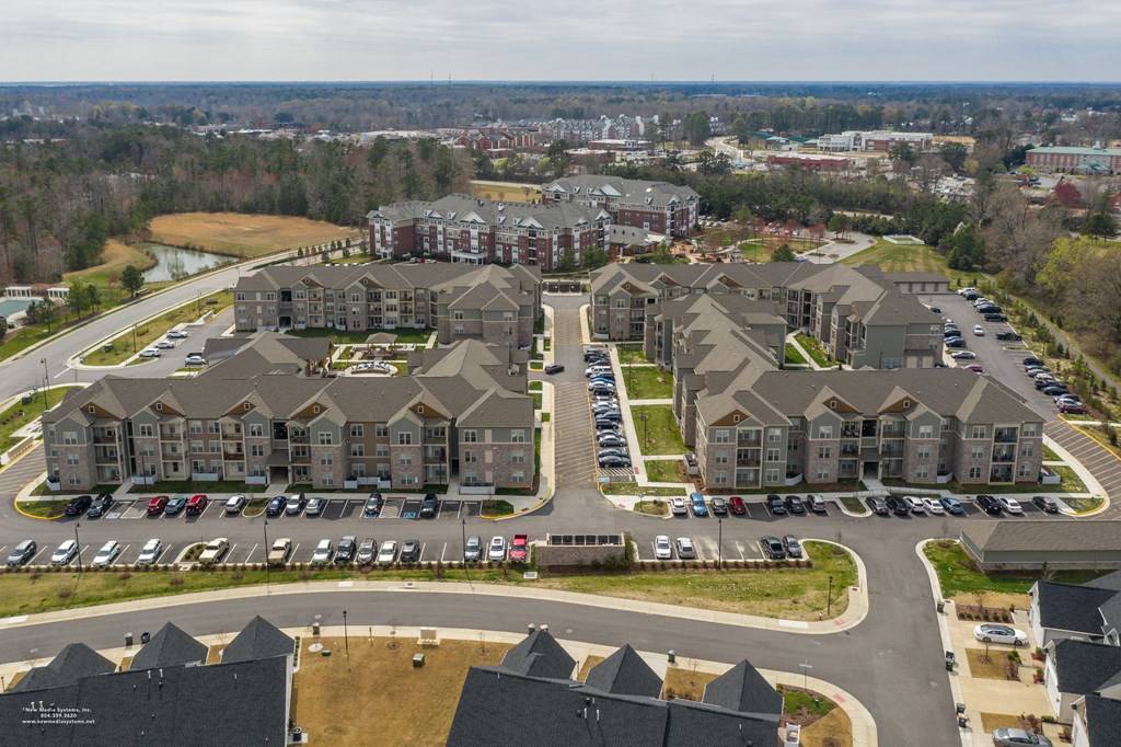 an aerial view of a large apartment complex with cars parked in a parking lot at The Whitworth, Williamsburg, VA, 23185