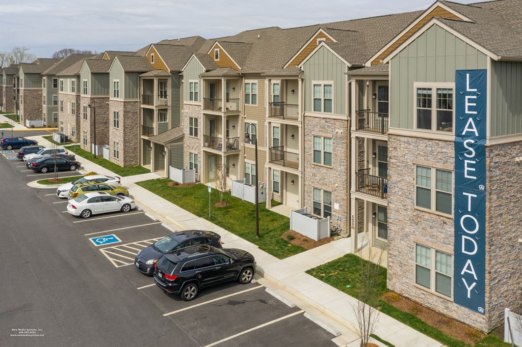an aerial view of an apartment complex with cars parked in the parking lot at The Whitworth, Williamsburg, VA