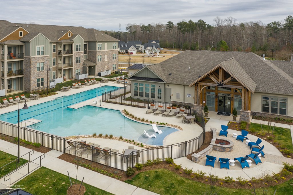 an aerial view of a resort style pool with lounge chairs and a clubhouse in the background at The Whitworth, Williamsburg, VA