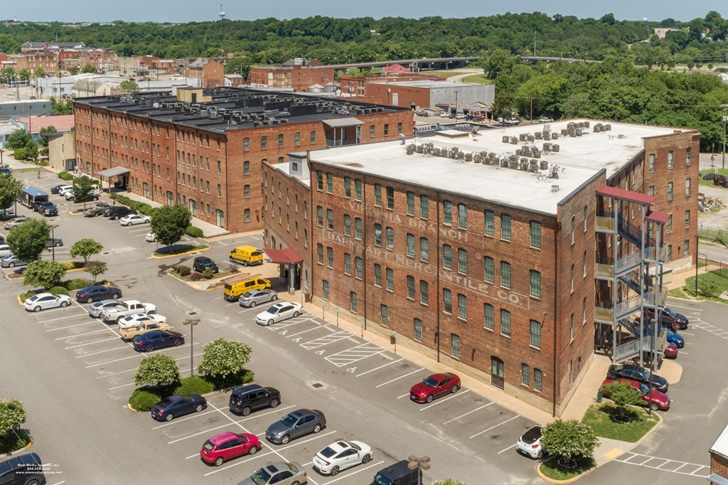 an aerial view of a brick building with cars parked in a parking lot at Mayton Transfer Lofts in Petersburg, VA 23803