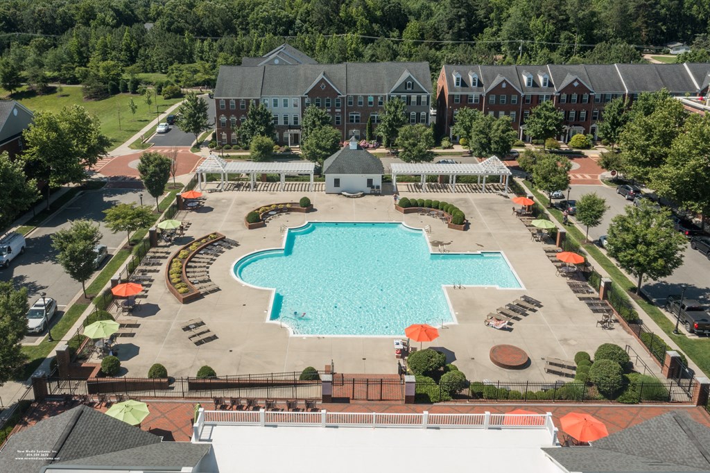an aerial view of a swimming pool in front of a hotel with trees