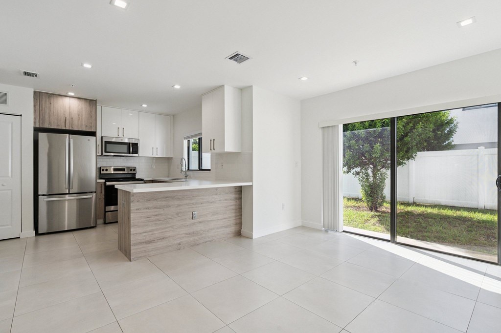A modern kitchen with a refrigerator, microwave, and oven.at The Villages at Miami Gardens, Florida