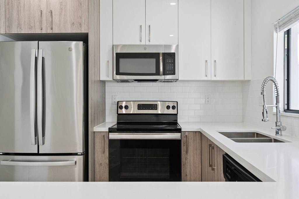 A modern kitchen with a stainless steel refrigerator, microwave, oven, and sink.at The Villages at Miami Gardens, Miami Gardens