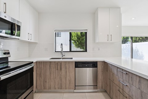 A modern kitchen with a stainless steel dishwasher and wooden cabinets.