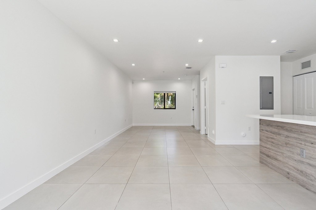 A spacious, empty room with white walls and a tiled floor.at The Villages at Miami Gardens, Florida, 33056