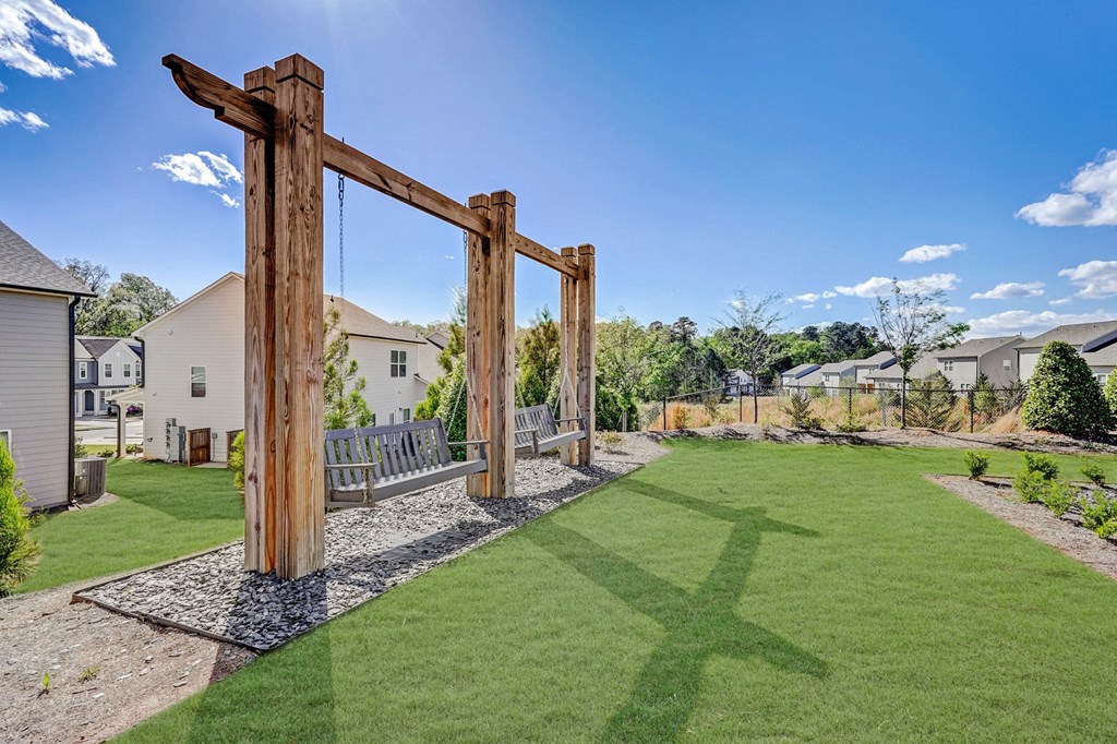 a backyard with a swing bench and a wooden arch