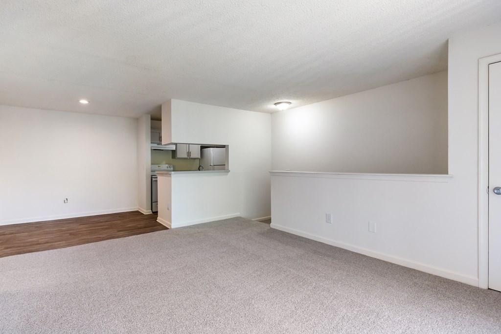 A spacious room with a white ceiling and a small kitchenette in the corner.