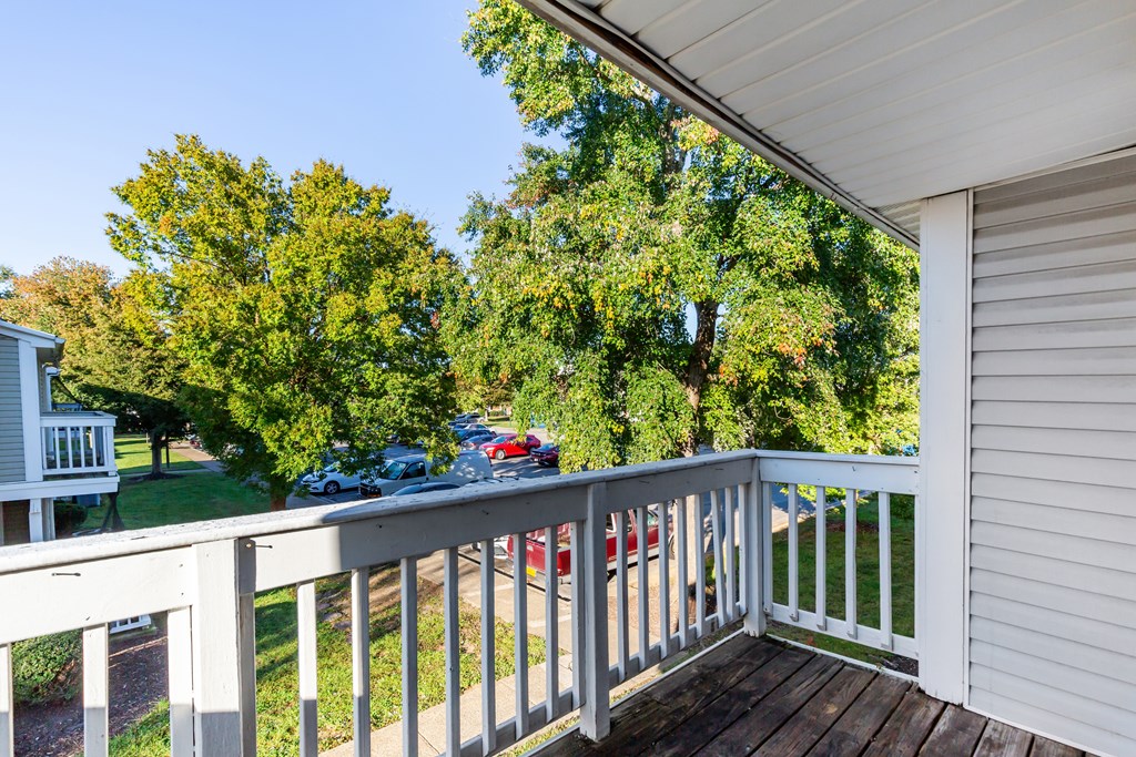 A white deck with a railing and a tree in the background.