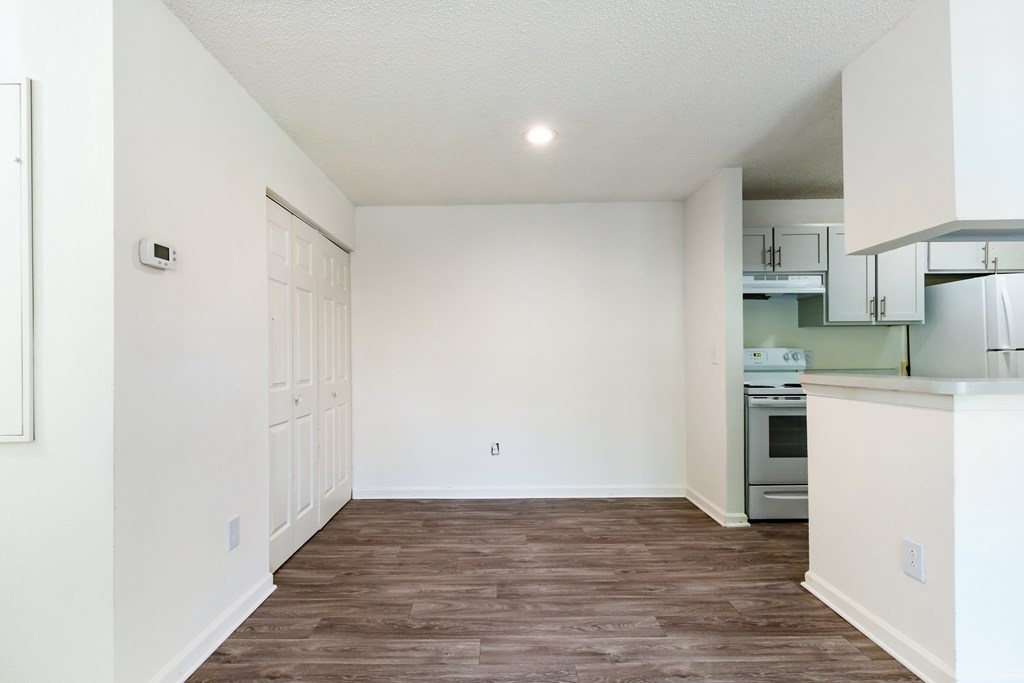 A kitchen with white walls and a wooden floor.