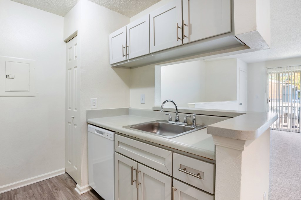 A kitchen with white cabinets and a marble countertop.
