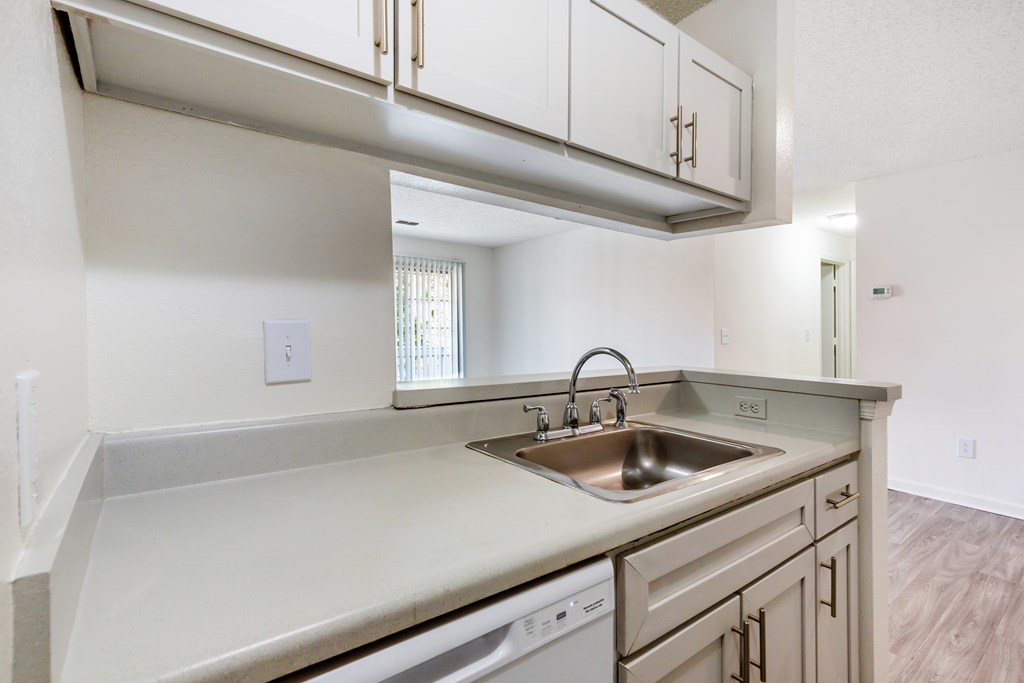 A kitchen with a sink, stove and cabinets.