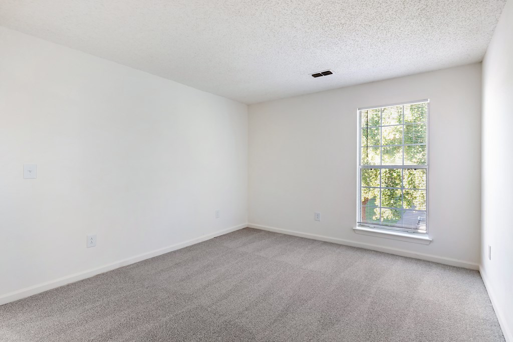 A room with a window and carpeted floor.