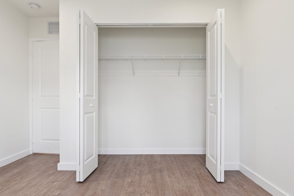 A white closet with a door open and a shelf above.at The Villages at Miami Gardens, Miami Gardens