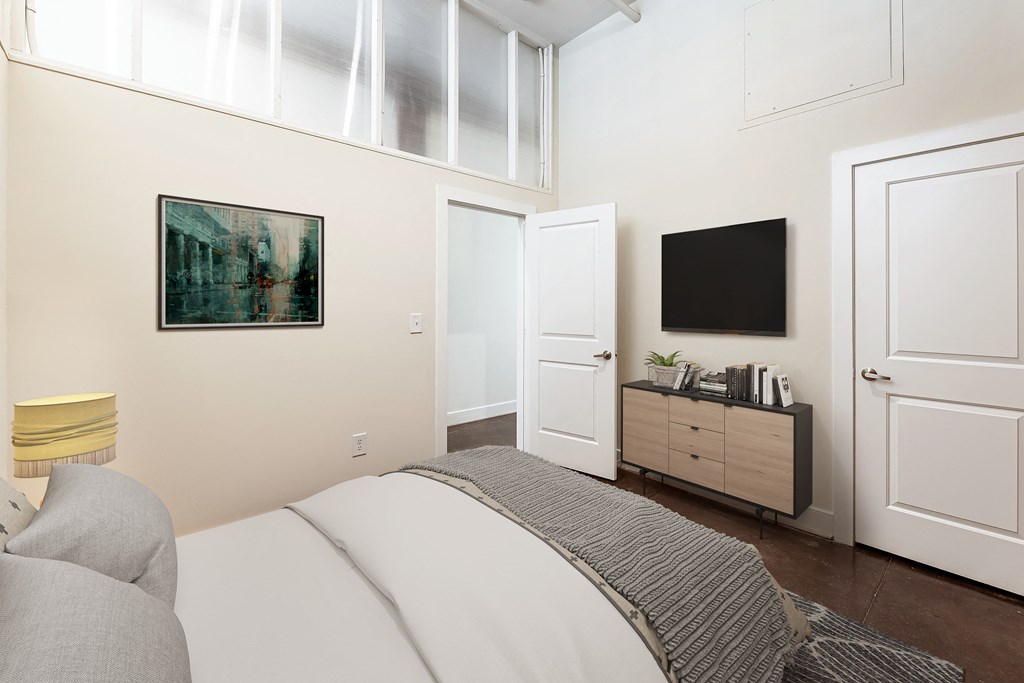 a bedroom with a bed and a tv on the wall at Mayton Transfer Lofts in Petersburg, VA 23803