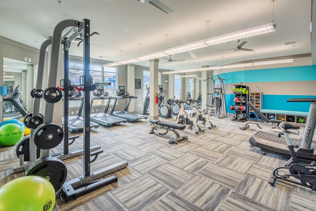 A gym with a variety of equipment including treadmills, weights, and exercise balls at Streets of Greenbrier, Chesapeake, VA