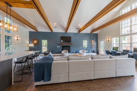 A large sectional sofa with a blanket on it sits in a spacious living room.