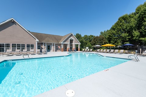 A large swimming pool in front of a building with a thatched roof.