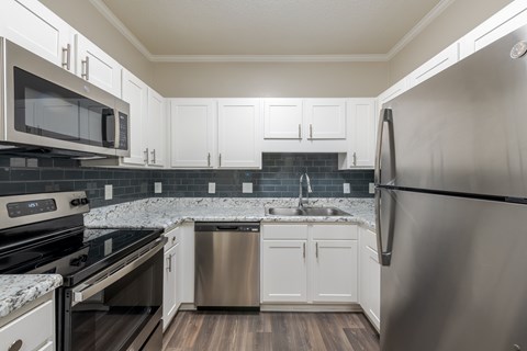A modern kitchen with white cabinets and stainless steel appliances.
