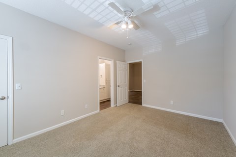 A room with a carpeted floor and a ceiling fan.